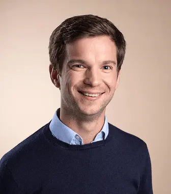 Portrait of a smiling man on a beige background.